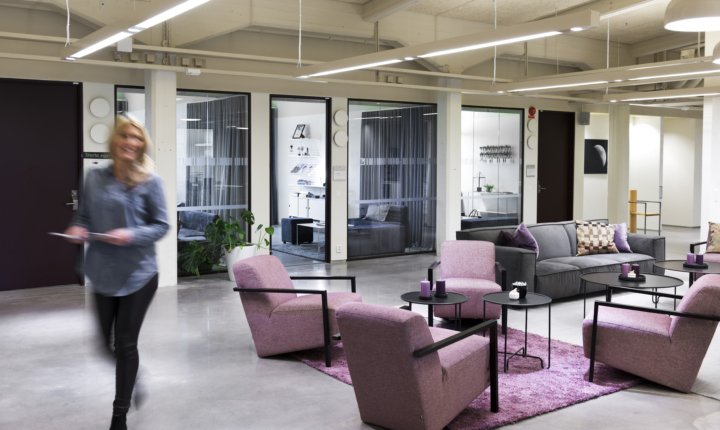 Interiörbild kontor med lila möbler med kvinna som går förbi